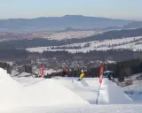 Snowboardziści na stoku, idealne miejsce, gdzie na narty z Wrocławia. W tle góry i miasteczko.