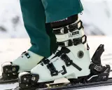 Jasne buty narciarskie Salomon z czarnymi klamrami na nartach.